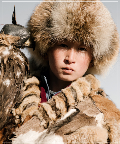 Zentralasien: Nomade in der Mongolei mit traditioneller Kleidung und Greifvogel bei einem Adlerfest